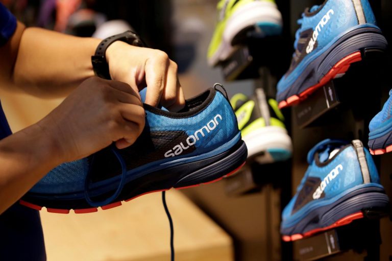 FILE PHOTO: A shop assistant holds a shoe at a Salomon store in Beijing, China August 10, 2018. Picture taken August 10, 2018. REUTERS/Jason Lee/File Photo